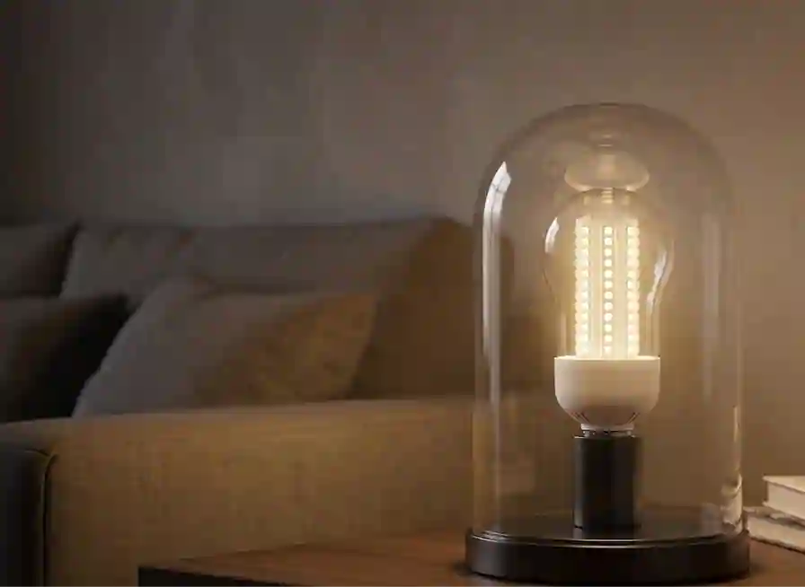 Rozsvícená LED žárovka vyzařující teplé bílé světlo v obývacím pokoji